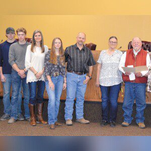Members of Scott Gleeson’s family — nephews August and Cyrus, sister in-law Jewel, niece Josephine, brother Mac, and parents Gayle and Bill Gleeson — accept a copy of a March 10 resolution approved by the Floresville City Council to name the city’s roping arena after Scott. GREGORY RIPPS/Wilson County News